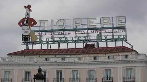 Iconic rooftop Tio Pepe sign in Madrid against cloudy sky, highlighting Stock Footage 334292676