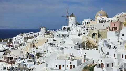Iconic whitewashed buildings and traditional windmills of Oia, Santorini. Stock Photos