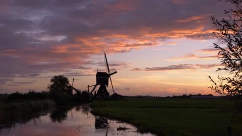 Iconic Windmill Silhouette Against a Dramatic Sunset Sky in the Netherlands Stock Footage 339545733