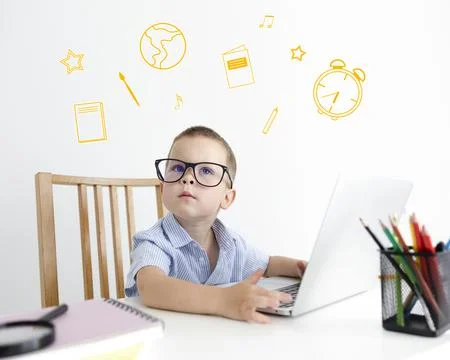 Icons hover over the boy sitting at his desk. Education concept. Stock Photos
