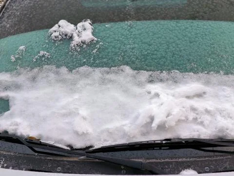Icy and snow-dusted windshield reflecting the winter chill. Stock Photos