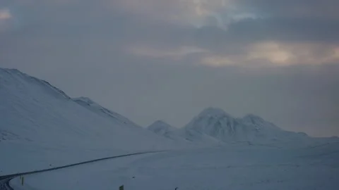 Icy Arctic highway cutting through Iceland's frosty tundra under overcast skies Stock Footage 302166547