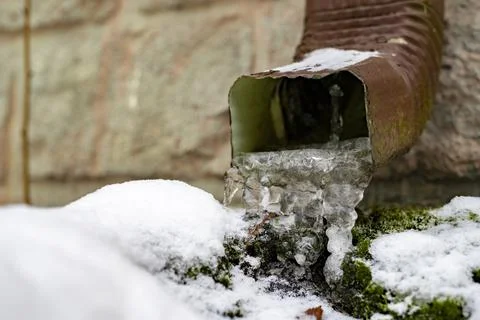 Icy gutter in a single-family house. Ice icicles in the drainage gutter. Stock Photos