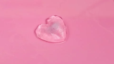 Icy heart melts against a solid pink background. Stock Footage 164072374