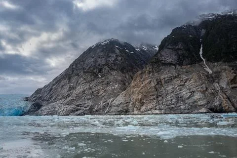 Icy water and lowering clouds surround the edge of Dawes glacier Stock Photos