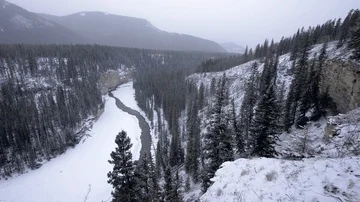 Icy winter river winds through canyon valley in snowstorm Video stock 85505043