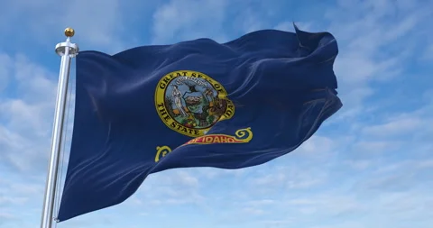 Idaho flag with flagpole waving in rolling clouds looping, 4K Perfect Loop 库存影片 280704335