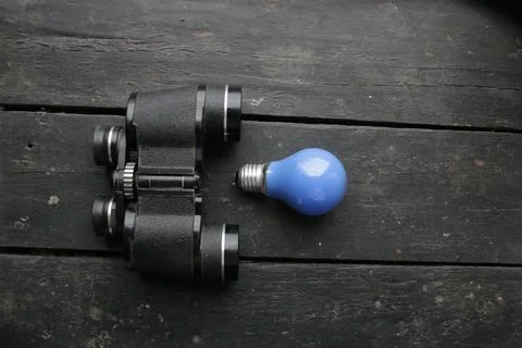 Idea concept. Binoculars and light bulb. Stock Photos