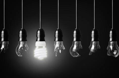Idea concept with broken bulbs and one glowing energy saving bulbs Stock Photos