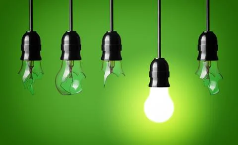 Idea concept with broken bulbs and one glowing bulb Stock Photos