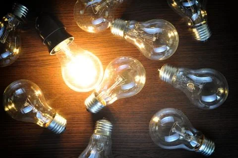 Idea concept with glowing bulb on brown wooden background Stock Photos