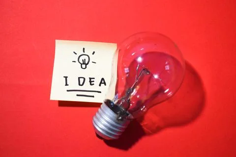 Idea on sticky notes and lightbulb. Isolated on red background with copy space Foto stock
