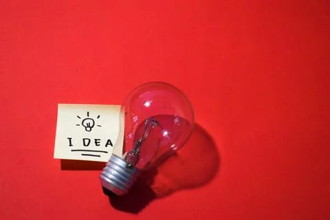 Idea on sticky notes and lightbulb. Isolated red background with copy space Foto stock