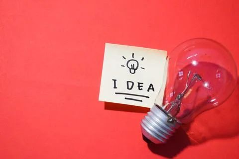 Idea on sticky notes and lightbulb. Isolated on red background and copy space Foto stock