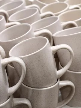 Identical ceramic cups in warm shades arranged in rows on retail store shel.. Stock-Fotos