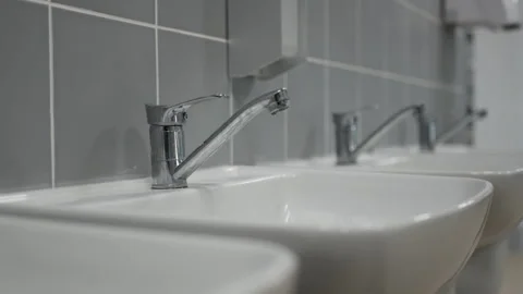 Identical sinks stand in clean row along grey tiled wall Stock Footage 335643874