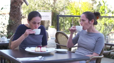 Identical twins sitting in a cafe, drinking coffee Stock Footage 58609584