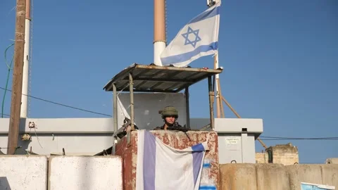 IDF soldier in security tower waves Israel flag and make kiss gesture Stock Footage 232366278