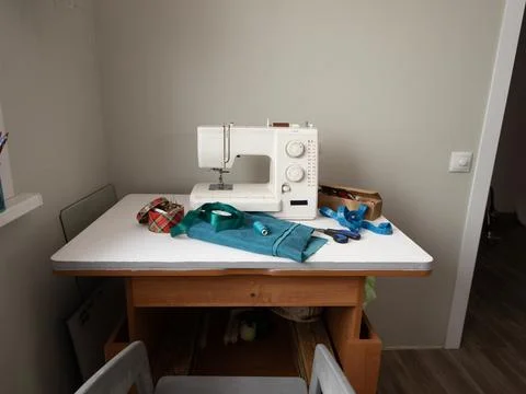 Idle sewing machine on organized worktable with fabric, ribbons, and tools Stock Photos