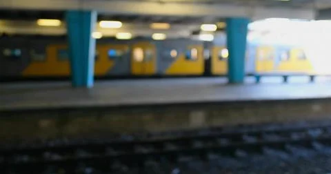 Idling yellow subway train resting on platform, with teal columns, overhead Stock Illustration