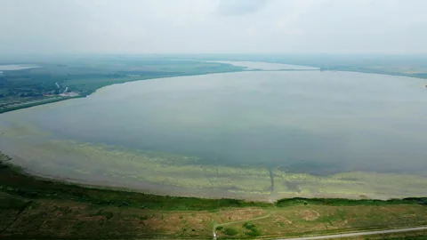 Idyllic aerial view of large round lake in cloudy day in plain countryside Video stock 263318496