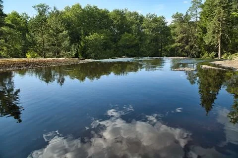 Idyllic lake with tree and cloud reflections in a clear natural setting Stock Photos