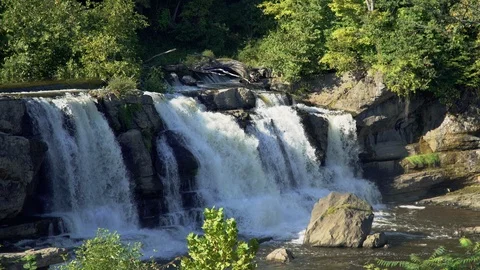 An idyllic moderate sized waterfall flows into a stream in upstate New York. Video stock 97304868