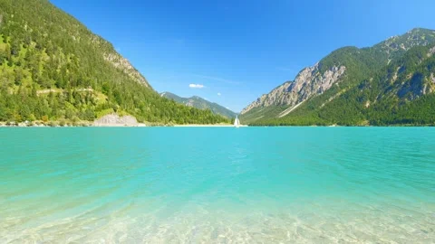 Idyllic mountain lake with transparent turquoise water, alpine meadows, and c Stock Footage 308317121