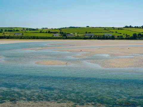 An idyllic view where green fields roll towards the water Stock Photos