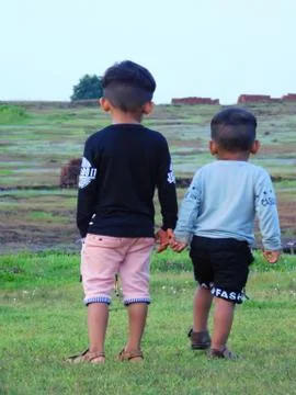 Iew of back side of two cute kids walking through the meadow Stock Photos