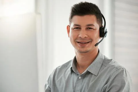 If the customers happy, Im happy. a young male call center agent at work. Stock Photos