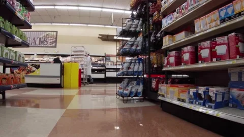 IGA retail grocery store worker with face mask pulled down handling a rack of Stock Footage 158288965