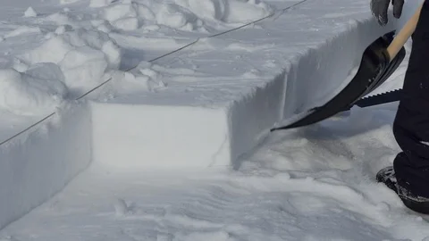 Igloo. A man picks up a carved snow block to build an Igloo. Close up. Stock Footage