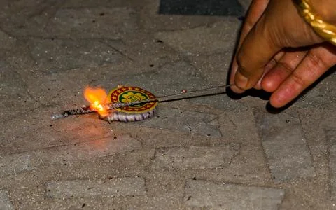 Igniting ground spinner with the help of sparkler during diwali Stock Photos