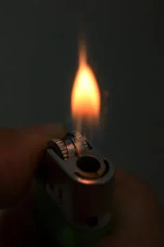 Igniting a lighter on a dark background. Stock Photos
