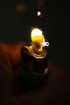Igniting a lighter on a dark background. Stock Photos