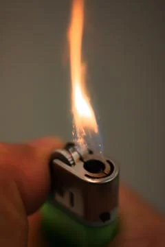 Igniting a lighter on a dark background. Stock Photos