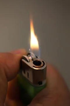 Igniting a lighter on a dark background. Stock Photos