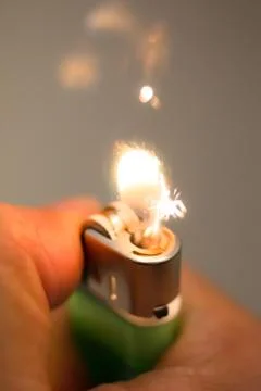 Igniting a lighter on a dark background. Stock Photos