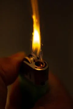 Igniting a lighter on a dark background. Stock Photos