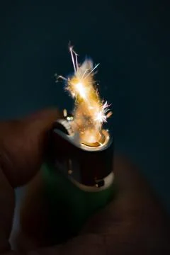 Igniting a lighter on a dark background. Stock Photos