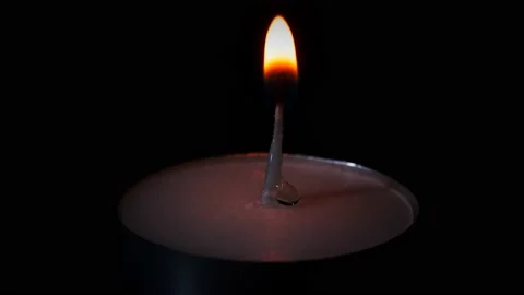 Igniting small round candle isolated on black background, flame burning 4K video Stock Footage 146763167