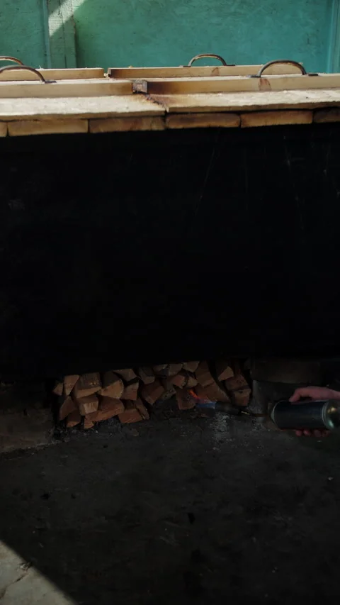 Igniting wood fire under closed fish smoking tank Stock Footage 306959803