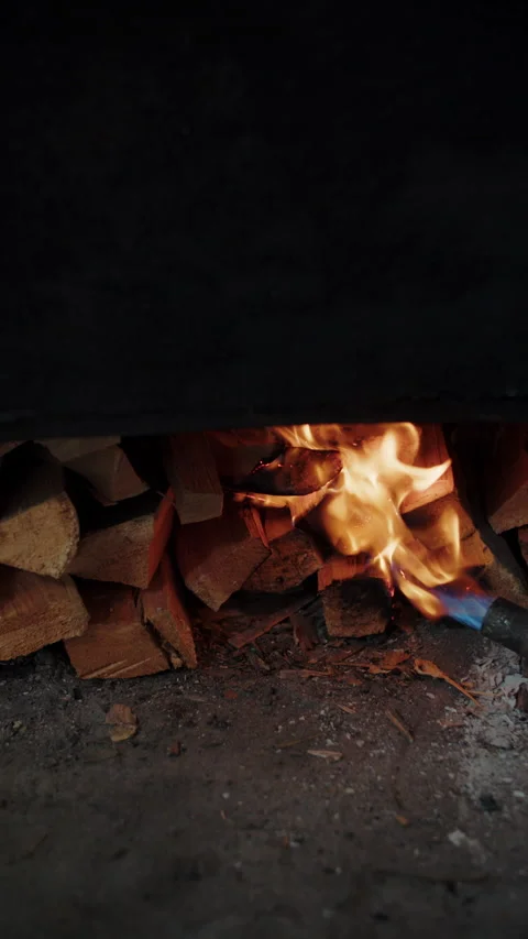 Igniting wood fire under closed fish smoker with torch Stock Footage 306960503