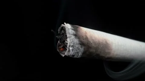 cigarette lit up Ignition and smoke from a lit cigarette and ash Close-up on a black  background