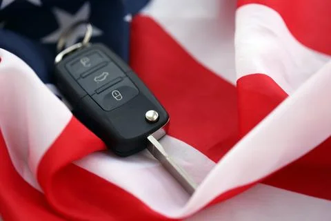 Ignition keys with remote control buttons on United States flag. Concept of car Stock Photos