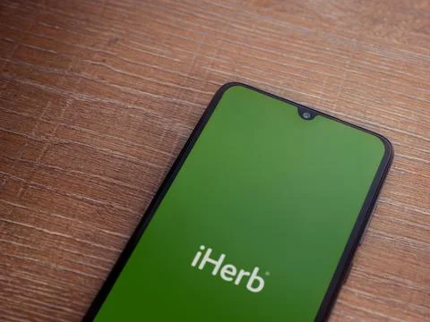 IHerb app launch screen on smartphone on wooden background Stock Photos