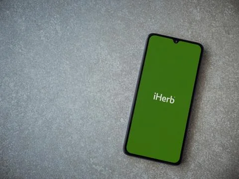 IHerb app launch screen on smartphone on ceramic stone background Stock Photos