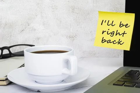 I'll be right back written on a yellow sticky note at the office. Stock Photos
