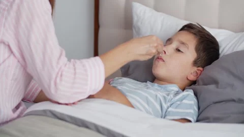 An ill boy feel weakness, takes medicinal drops orally, looks at mom and lies Stock Footage 255424307